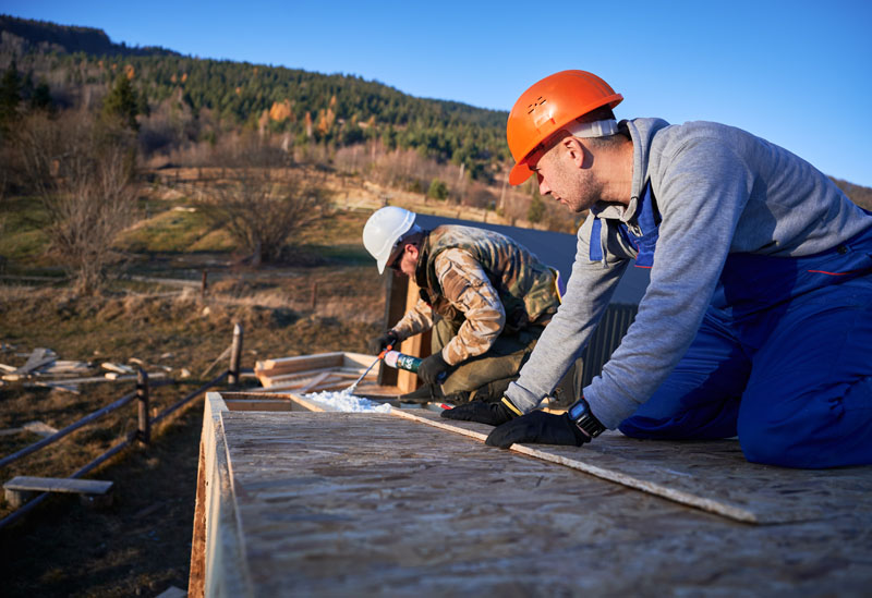 Male builder doing thermal insulation on roof of wooden frame house by polyurethane foam. Solar Leads process
